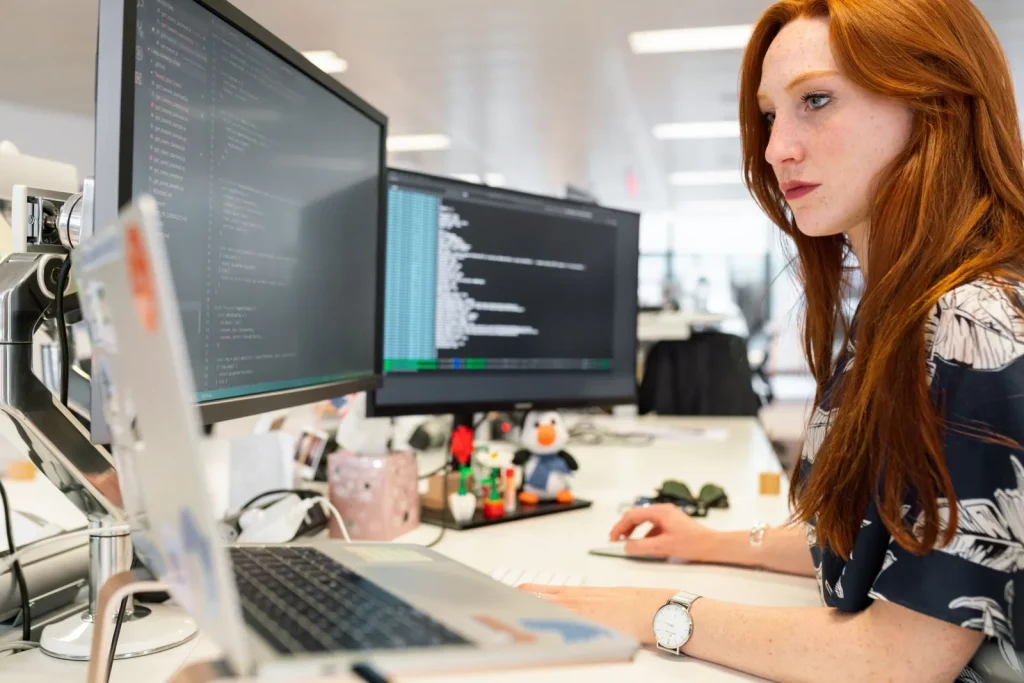 Software engineer working across dual monitors in a modern engineering office