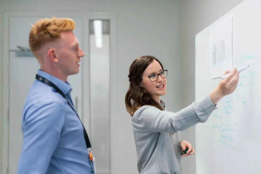 Colleagues working through a problem at a whiteboard during discovery