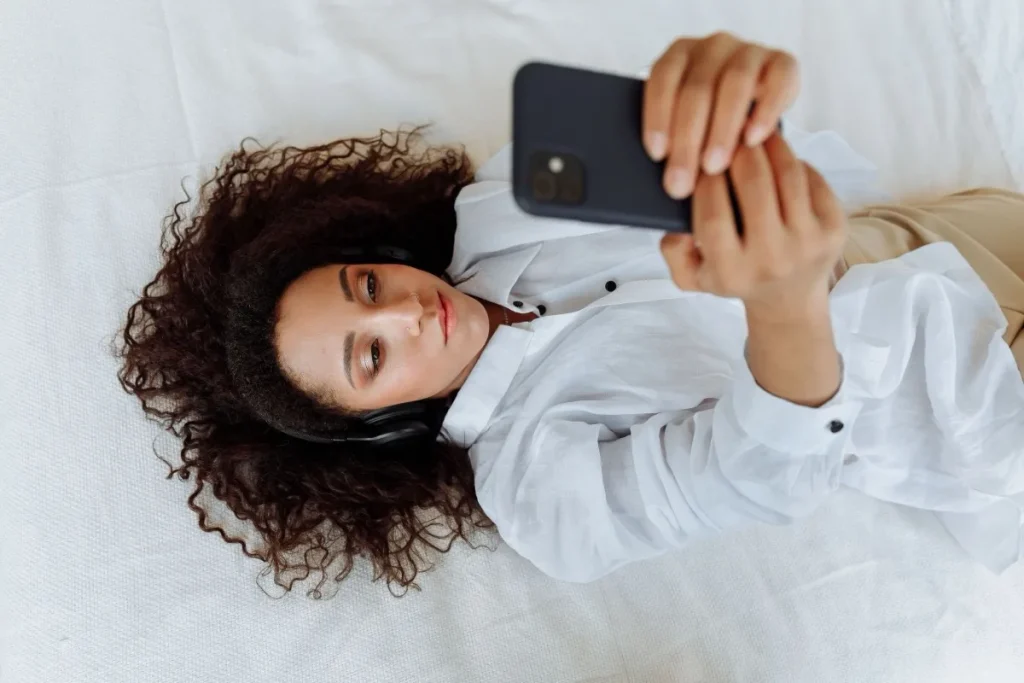 A young woman with headphones watching a series on her smartphone