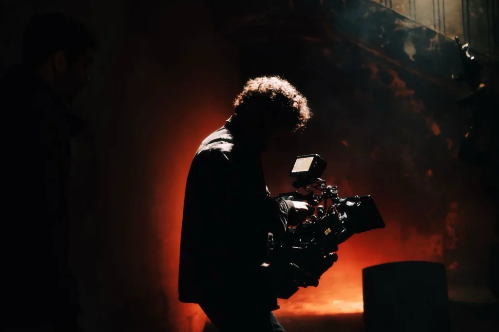 A camera operator filming a scene on a creatively lit production set