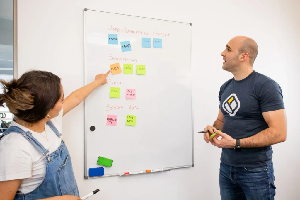 Two colleagues structuring requirements on a whiteboard of sticky notes